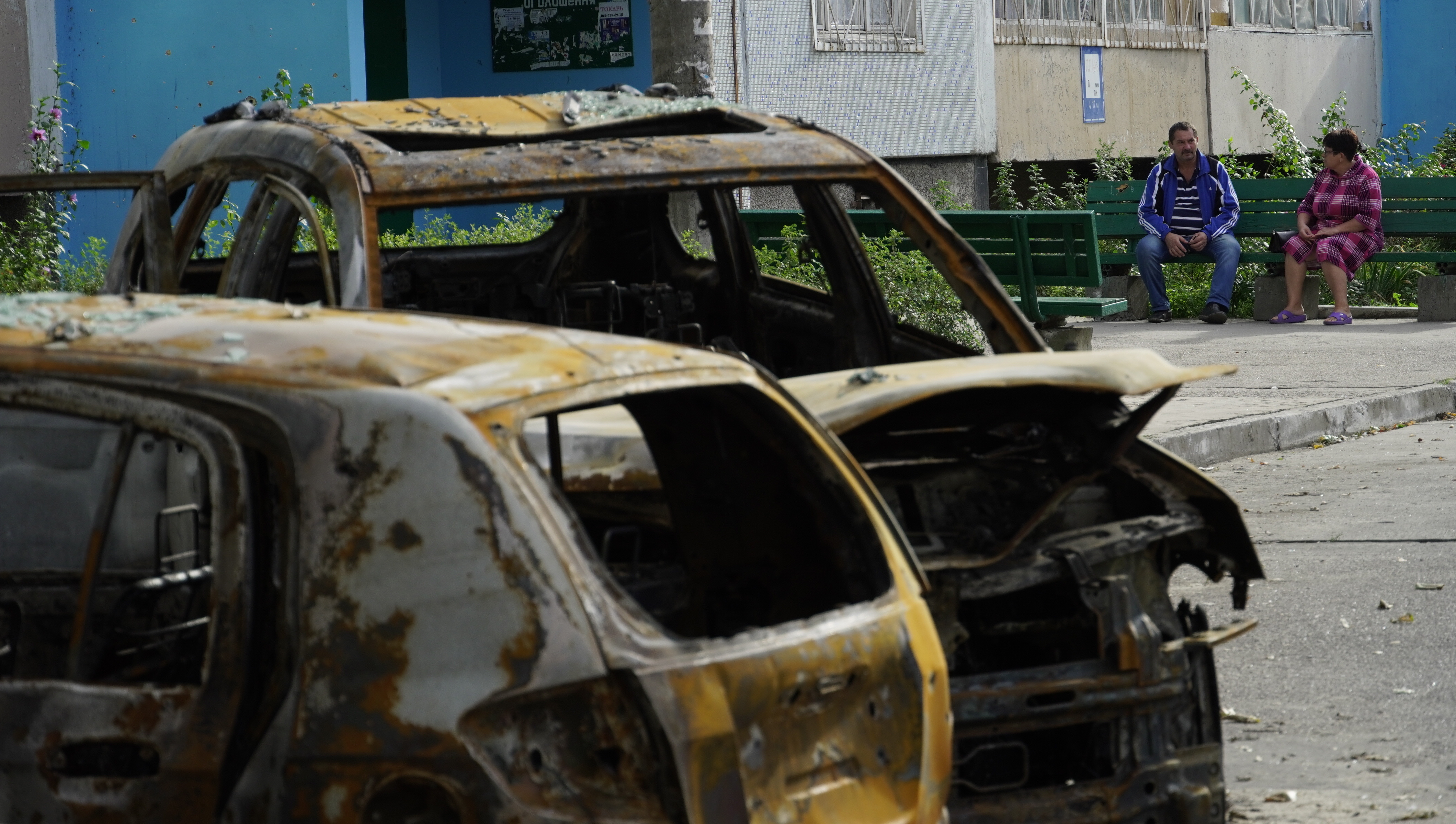 Enerhodar Two locals discuss on a bench behind damaged vehicles in Enerhodar, near Zaporizhzhia on Sept. 11, 2022. (Anadolu Agency/Getty Images)