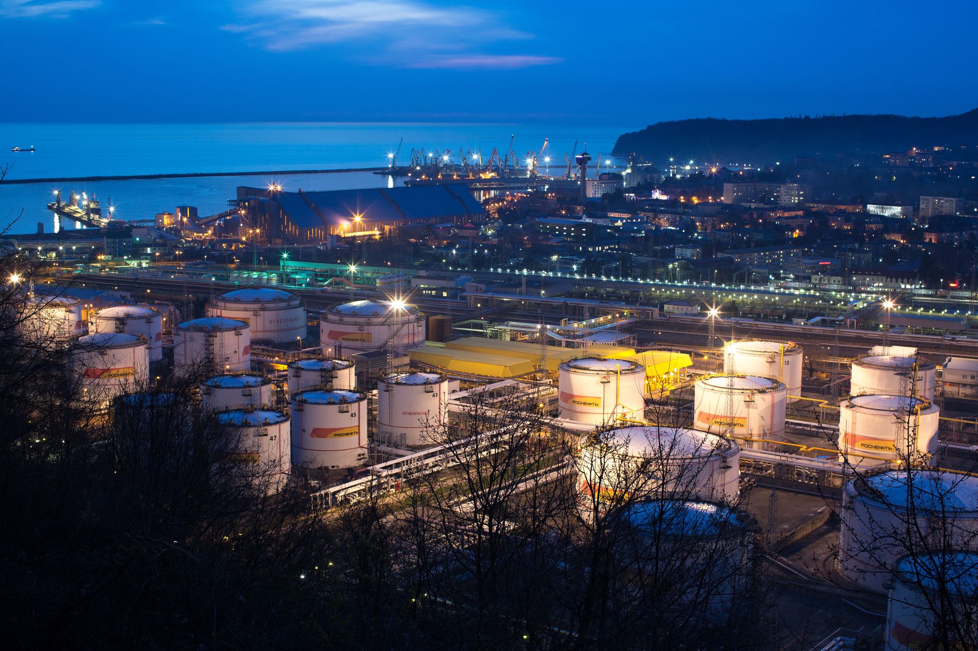 Oil storage tanks stand illuminated at night at the RN-Tuapsinsky refinery, operated by Rosneft Oil Co., in Tuapse