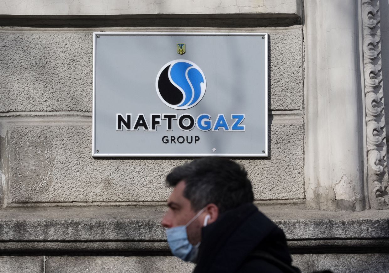 A man walks past the Naftogaz logo.