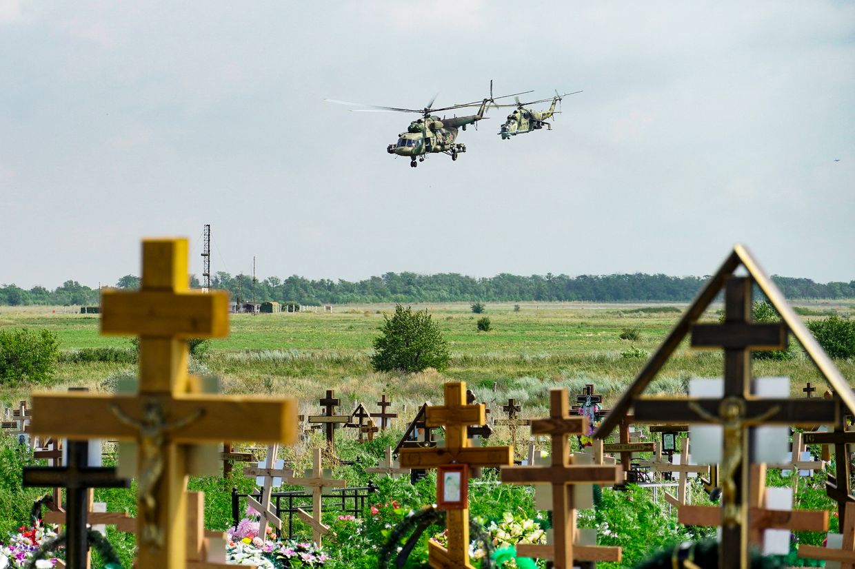 Russian military helicopters painted with the letter Z, a tactical insignia of Russian troops in Ukraine, are seen flying behind a cemetery near a military airfield outside Taganrog in the Rostov region on July 26, 2022