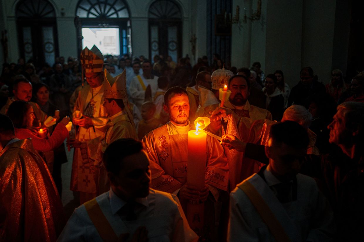 Believers light their candles from the Easter Candle at the Easter Vigil mass at the Roman Catholic Parish in Kyiv