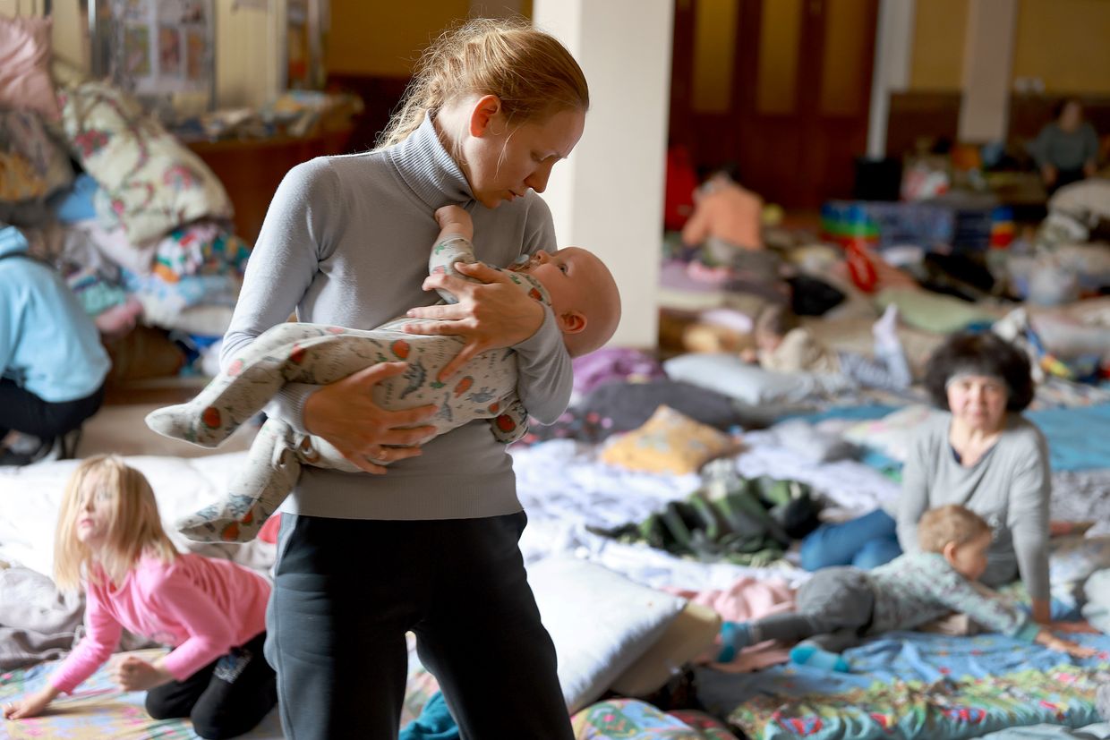 Xenia (who did not want to provide her last name) comforts her baby Alexander while they rest at a temporary refugee center set up at the main train station in Lviv