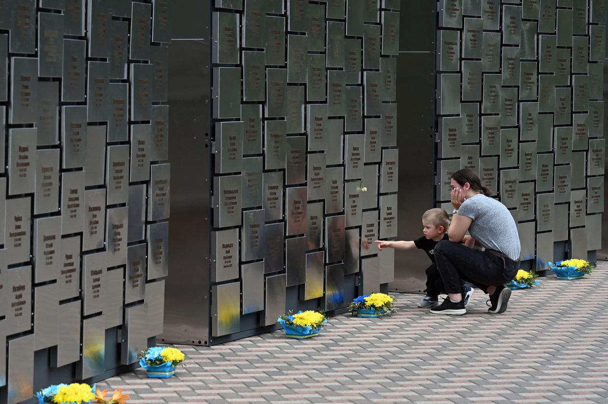 A young woman reacts as she stands with her son in front of a recently inaugurated monument, including 501 plates with 
