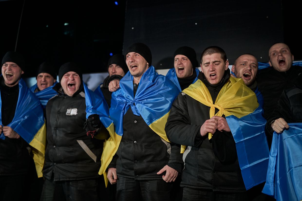 Men sing during a night-time exchange of prisoners of war in an undisclosed location in Ukraine on Feb. 8, 2024