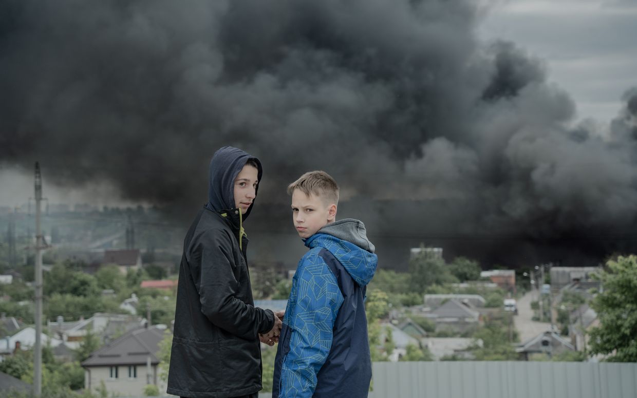 Boys watch as smoke rises over the city following Russian bombs in Kharkiv, Ukraine