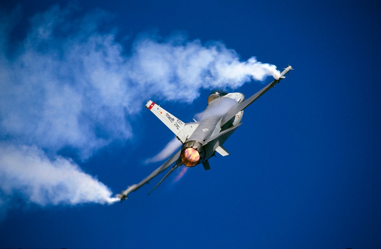 U.S. F-16 Fighting Falcon fighter during a high-g flypast with smoke trails