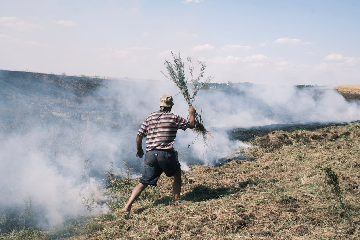 Enver, 46, a local resident, helps to put out the fire in the wheat fields, burning after the shelling in the village of Nova Poltavka, Ukraine, on July 2, 2024.