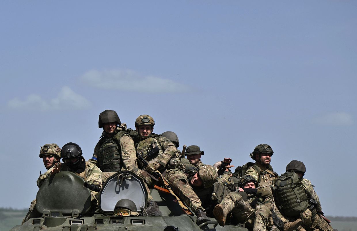 Ukrainian servicemen ride on an armored personnel carrier (APC) in a field near Chasiv Yar, Donetsk oblast