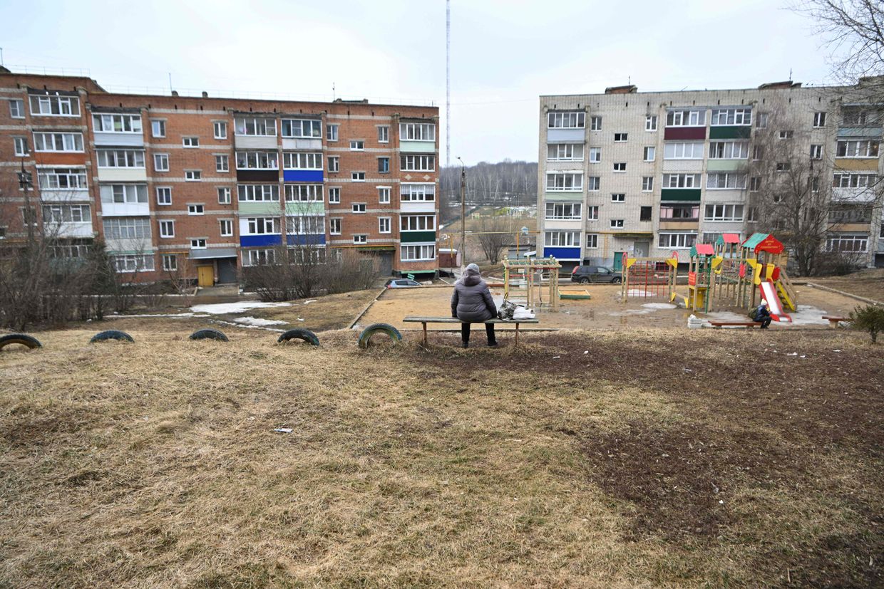 A woman sits on a bench in a residential area in the town of Yefremov in the Tula region