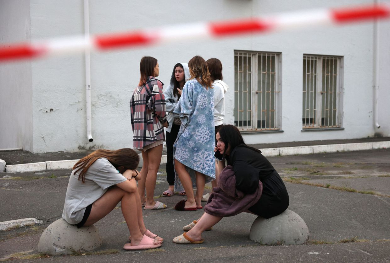 Students of the International Academy of Personnel Management watch emergency teams work to extinguish a fire