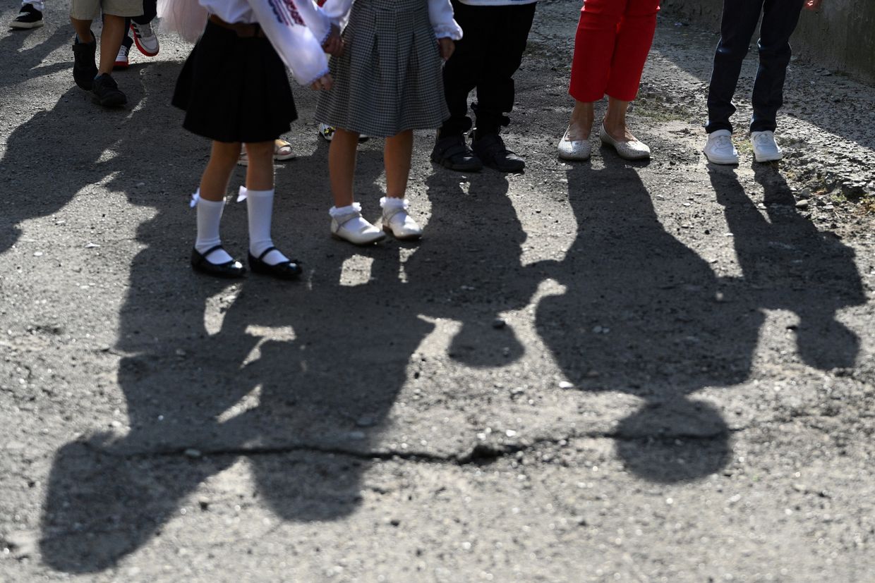 The shadows of Ukrainian schoolchildren attending a bell ceremony on the first day of the new school year 