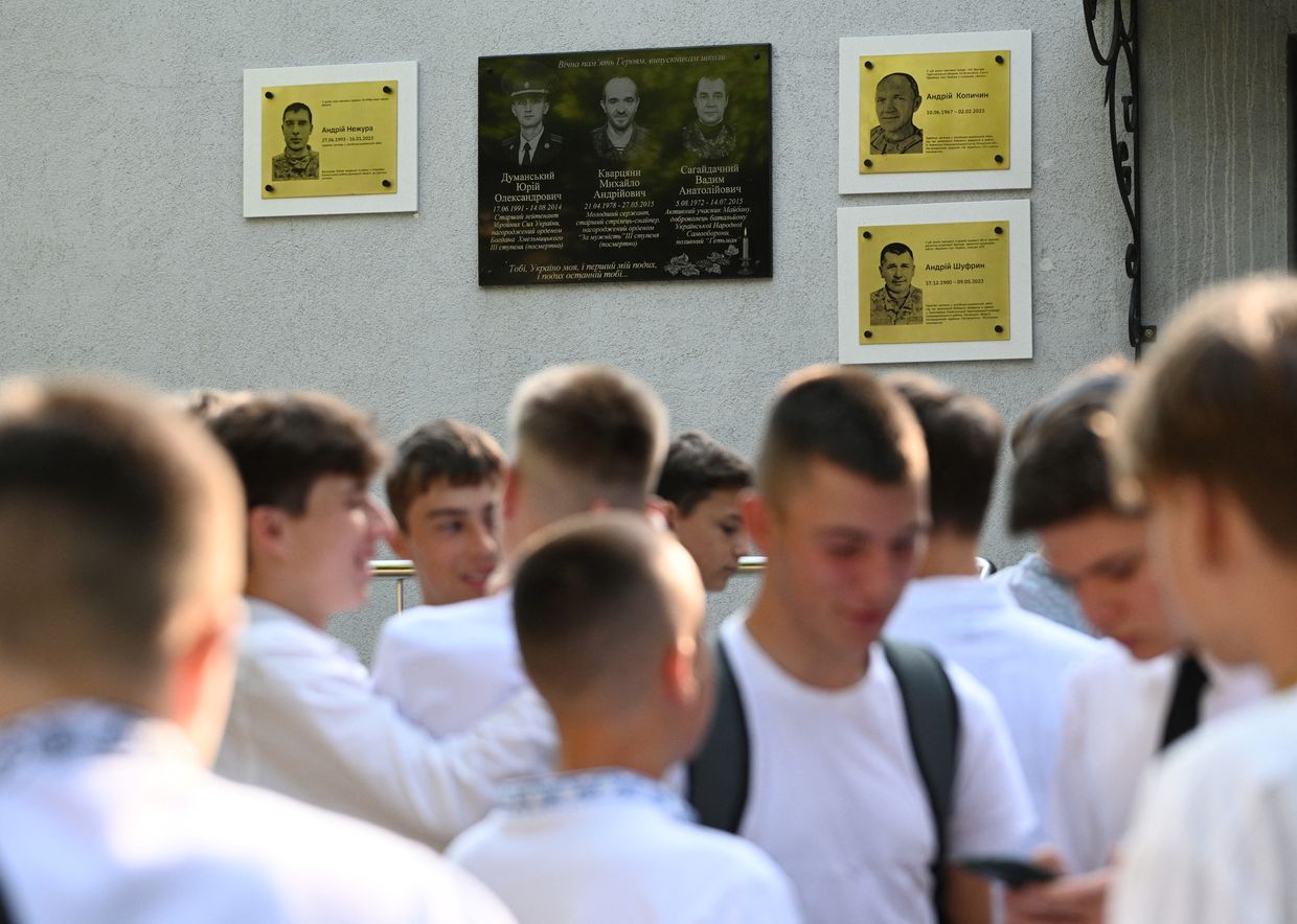 Pupils stand in front of memorial plaques for late students from the lyceum who died during the war 