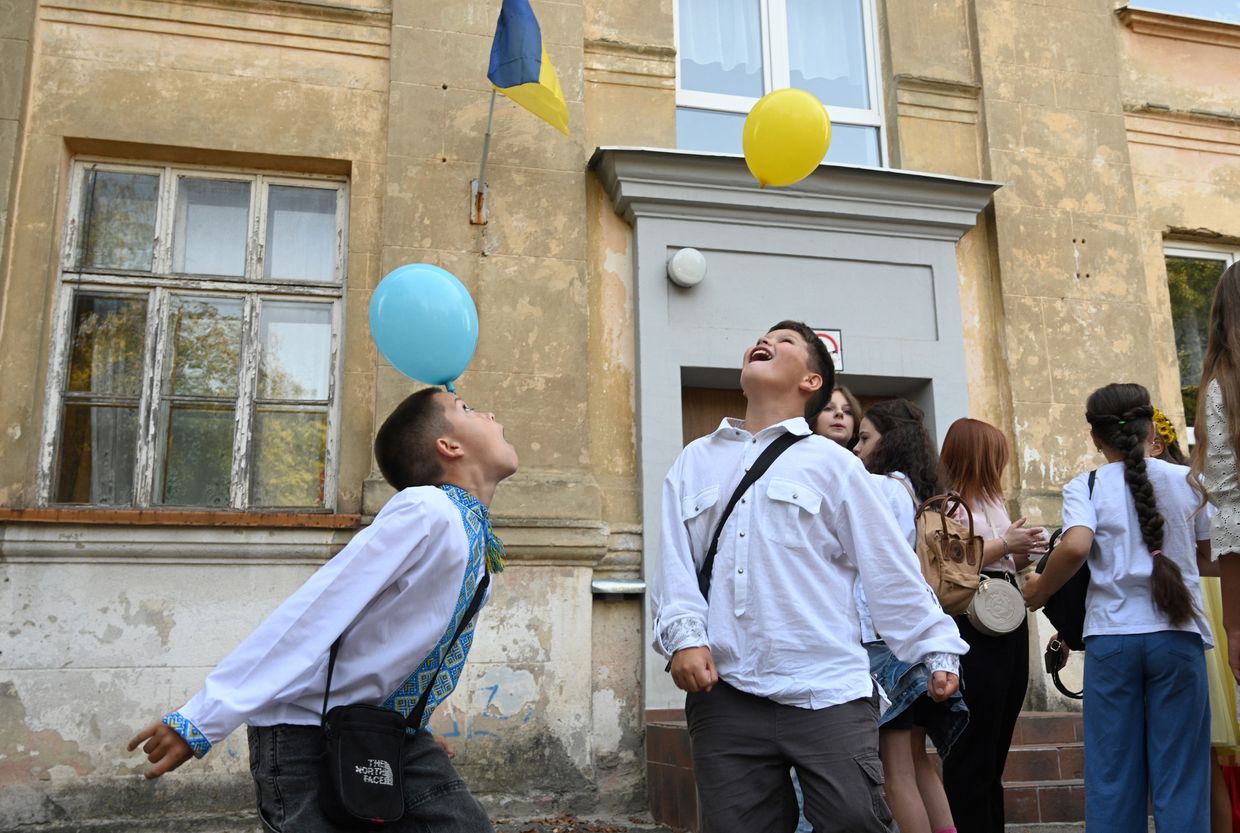 Ukrainian children play in the schoolyard before a bell ceremony on the first day of the new school year in Lviv