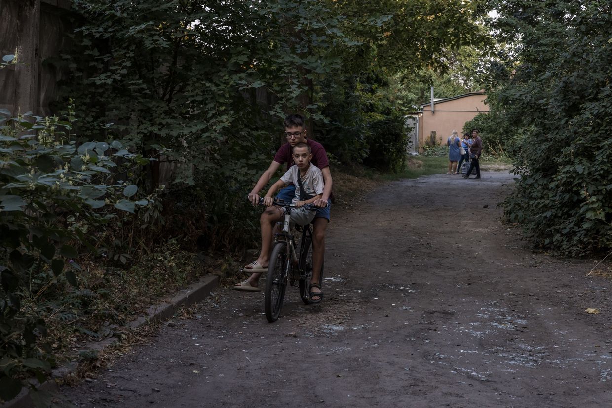 Kids ride the bike near the broken glass from the residential building located near the Military Institute of Telecommunications and Information Technology