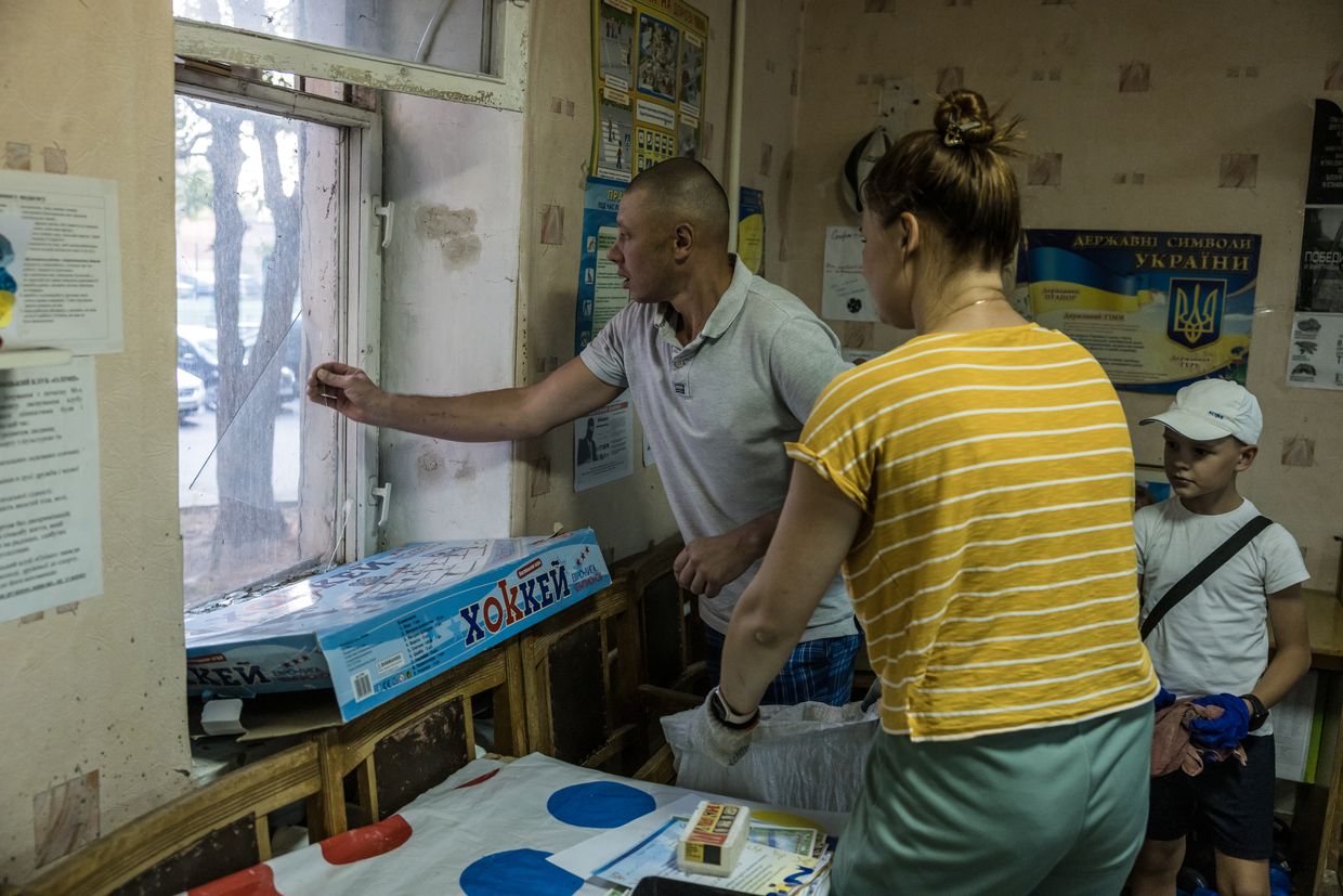 Rostyslav Lypii, 30, and Natalia Hetalo, 32, clear away shards of glass from broken windows at the taekwondo school their children attend in Poltava, Ukraine, September 3, 2024. 