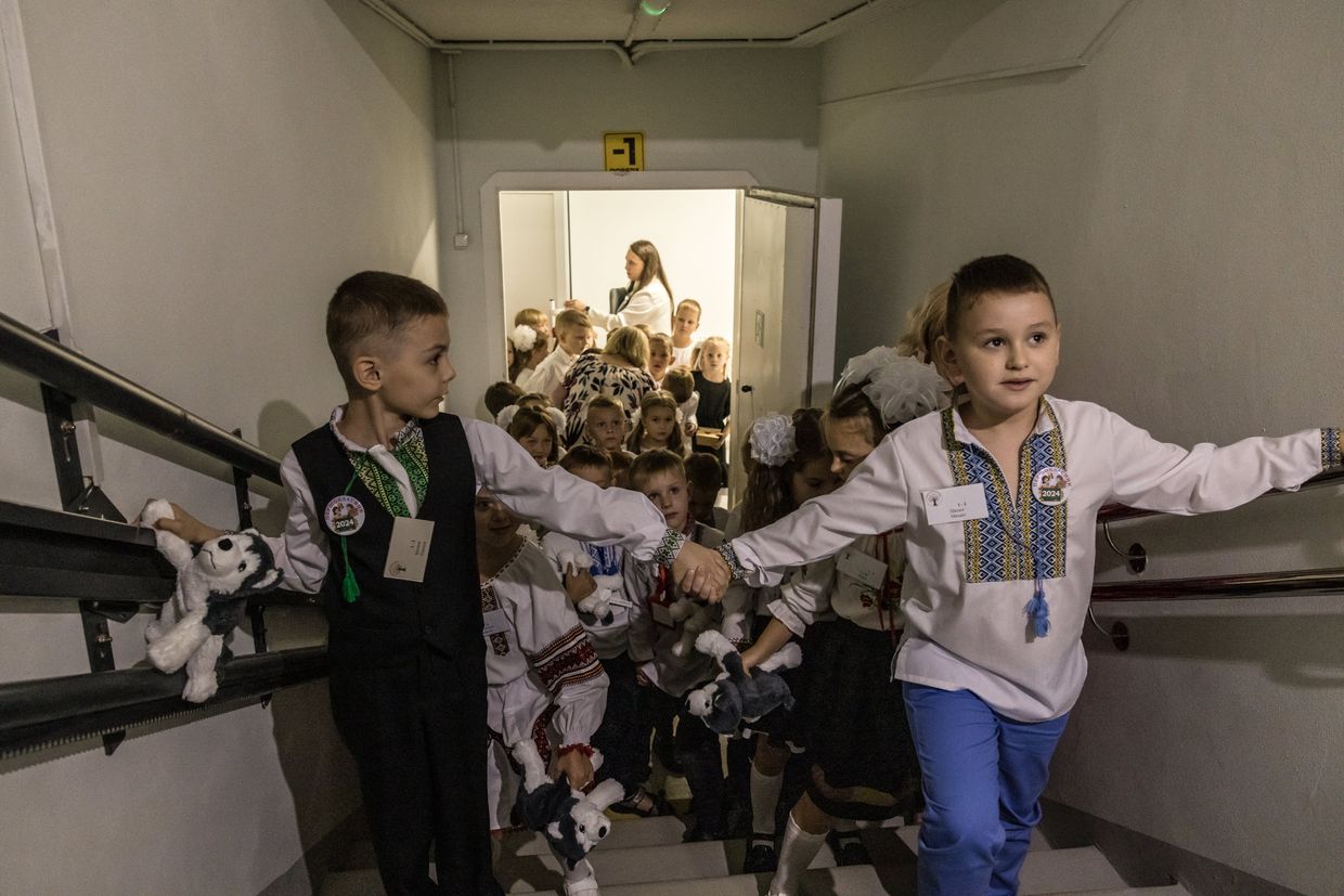 Los niños de primer grado salen de la escuela subterránea después del primer día de festividades escolares. 