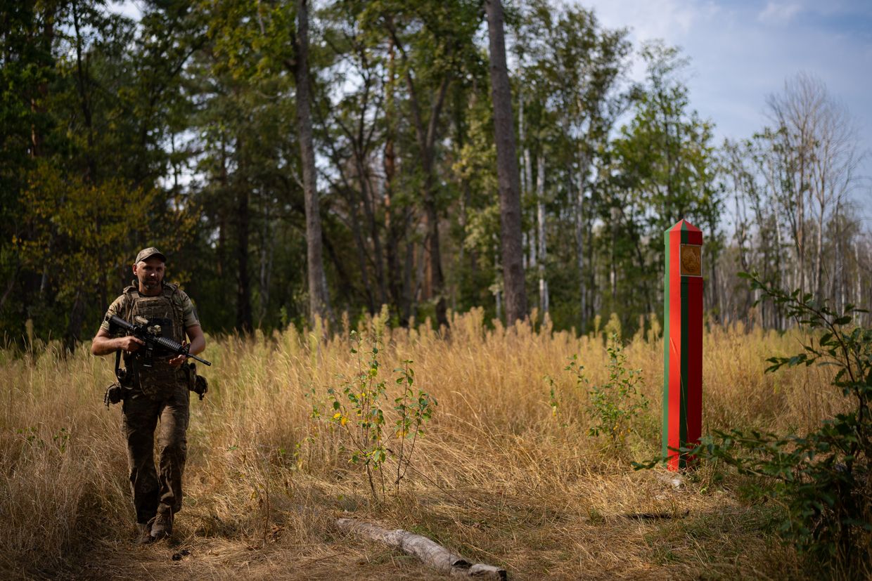 A serviceman of the 78th Air Assault Regiment near a border post painted in the colors of the Belarusian flag in Chornobyl zone, Kyiv Oblast