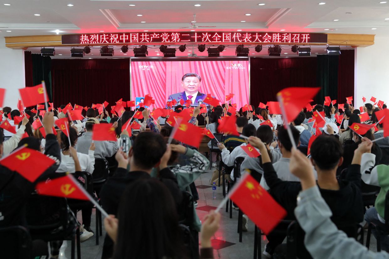 People are waving national flags and Communist Party flags as they watch the opening session of the 20th Chinese Communist Party Congress