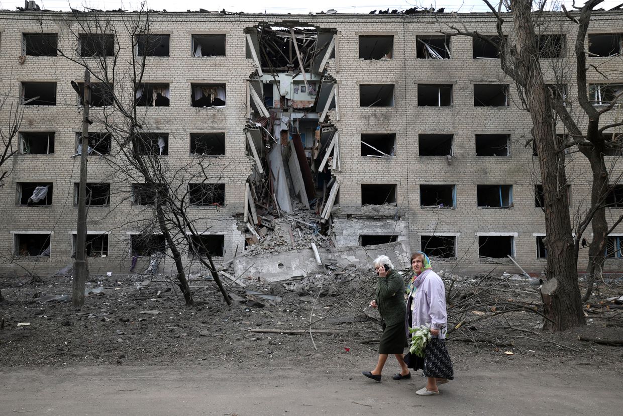 Elderly women walk past a hostel destroyed during a missile attack in the town of Selydove, Donetsk region, on April 14, 2024