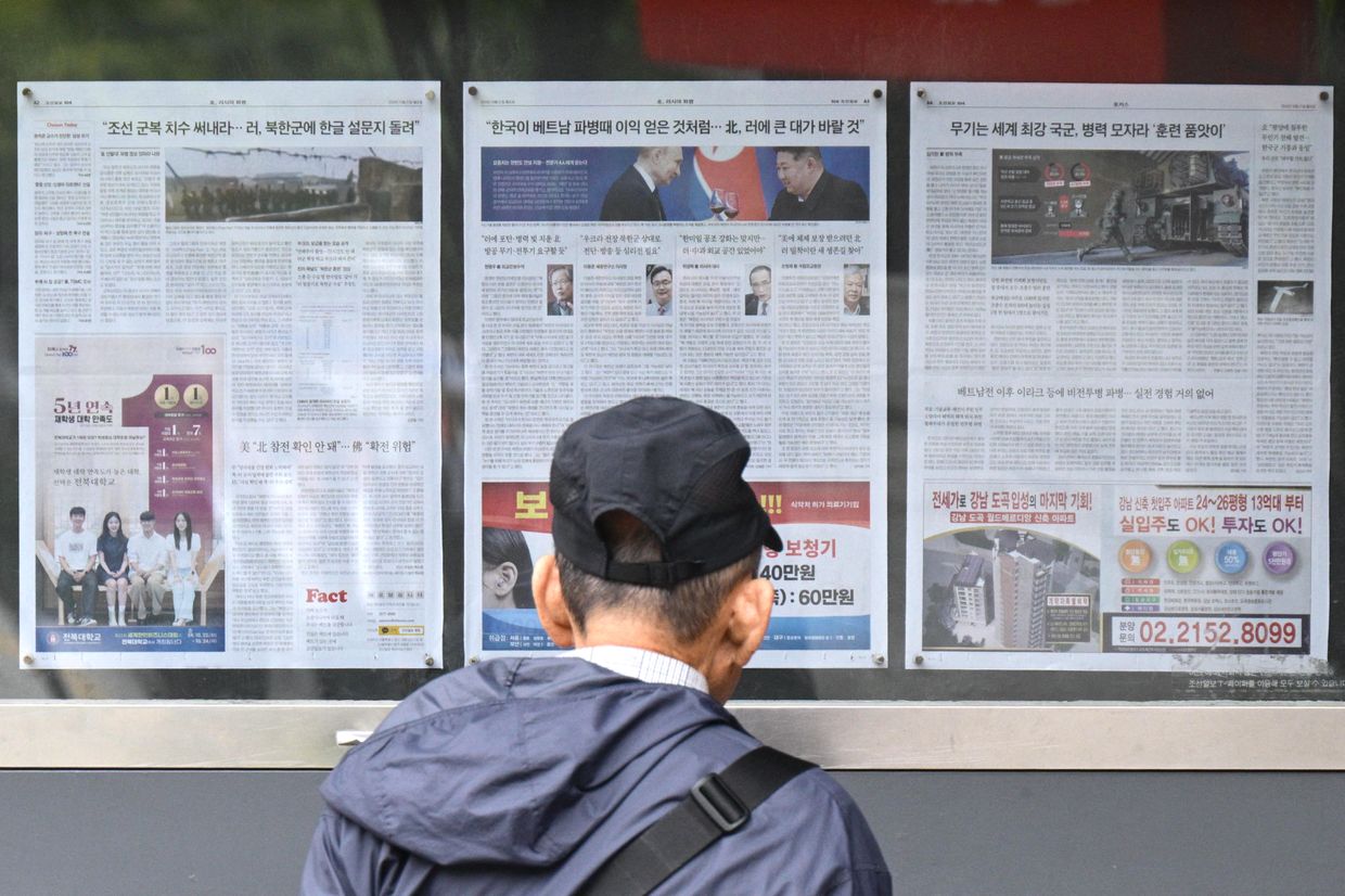  A man walks past a newspaper in Seoul on Oct. 21, 2024, showing Kim Jong Un and Putin toasting after North Korea's troop deployment.