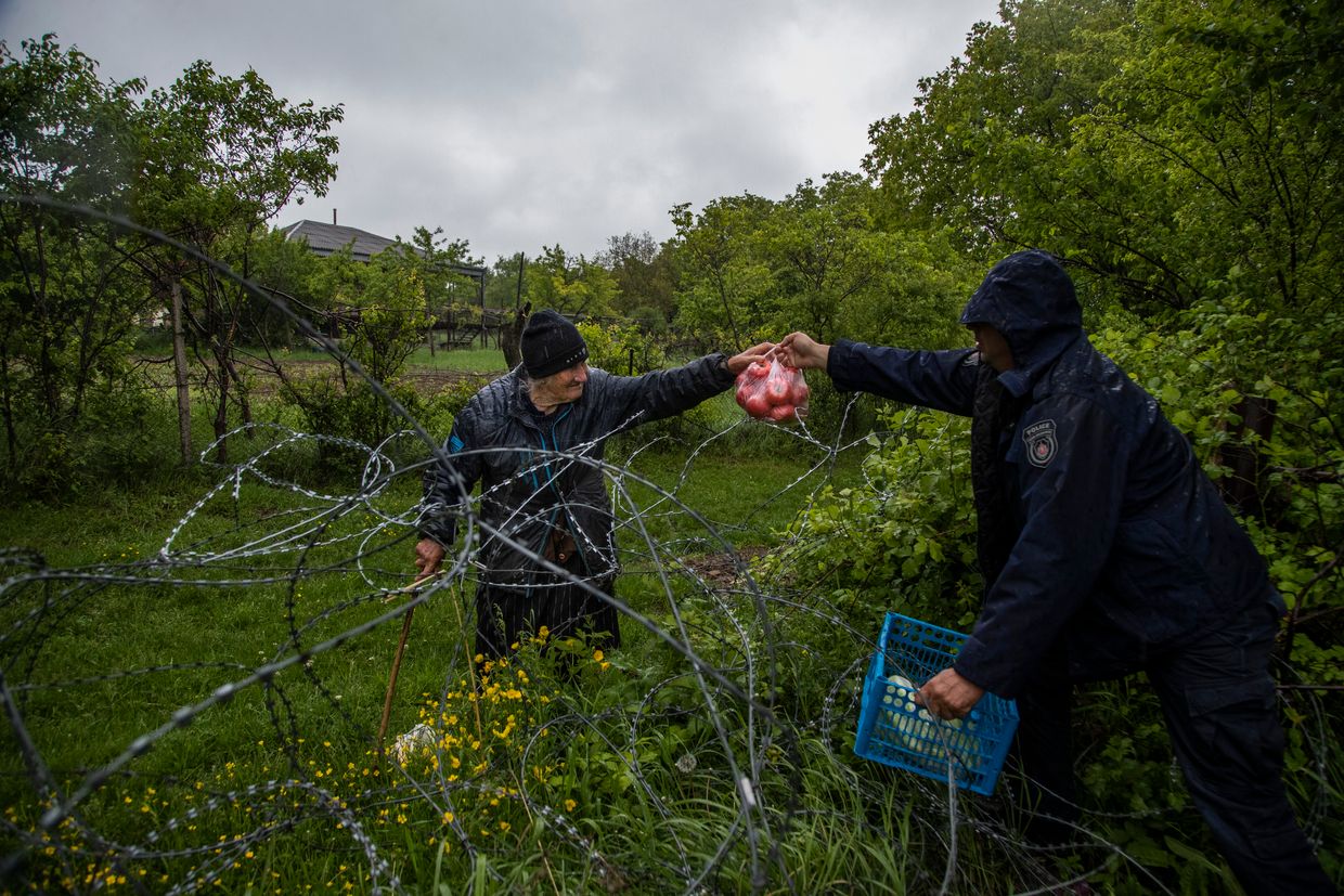 Georgian border police hand food over a barbed wire fence to a local farmer, who stands on the Russian-controlled territory of South Ossetia in Khurvaleti village, Georgia on May 23, 2022.