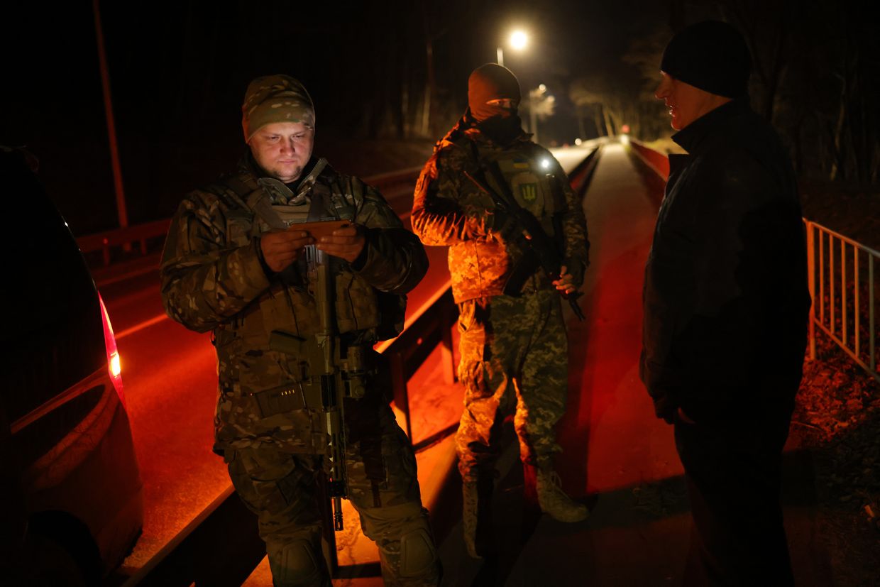 Yaroslav Kryvulya (L) checks digital ID documents of a man violating curfew in the early hours in Lviv, Ukraine, on Feb. 23, 2023.