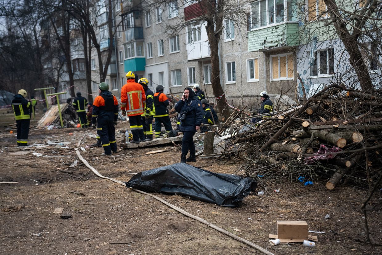 Rescuers stand near a dead body that was pulled from under the rubble in Sumy, Ukraine on March 14, 2024. 