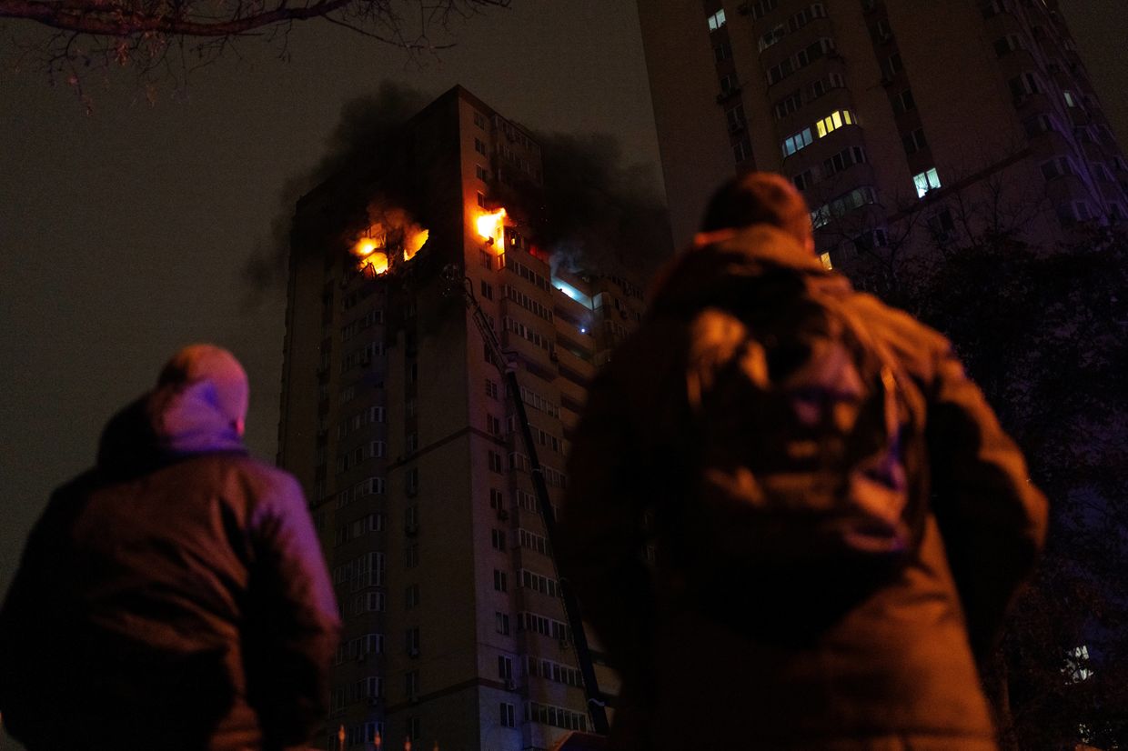 People watch as firefighters extinguish a fire in a Kyiv high-rise reportedly hit by a drone on Oct. 25, 2024, amid Russia’s invasion.