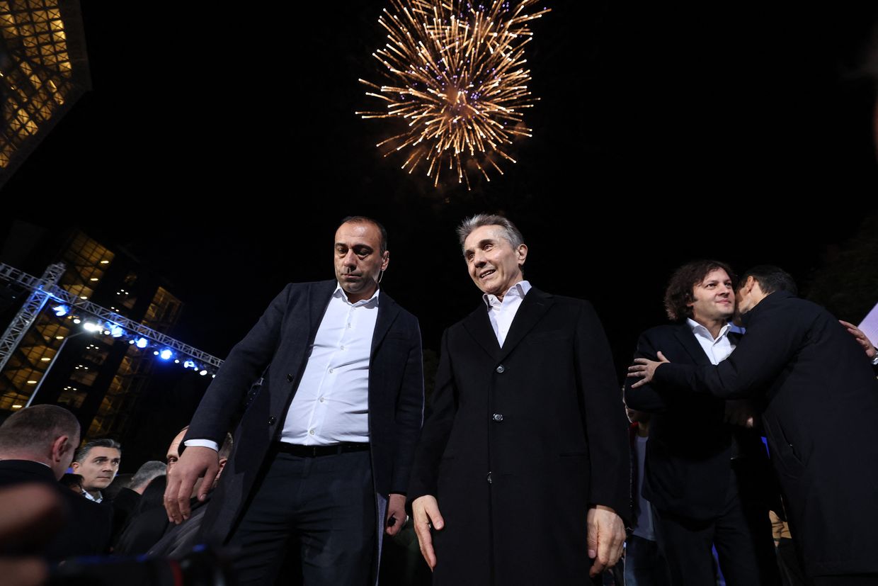 Georgian oligarch Bidzina Ivanishvili (C) and PM Irakli Kobakhidze (R) react to exit polls at Georgian Dream HQ after elections in Tbilisi, Georgia, on Oct. 26, 2024.