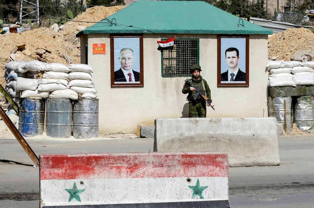 A Russian military police officer stands guard near portraits of Bashar al-Assad and Vladimir Putin at the Wafideen checkpoint near Damascus, Syria, on March 1, 2018.