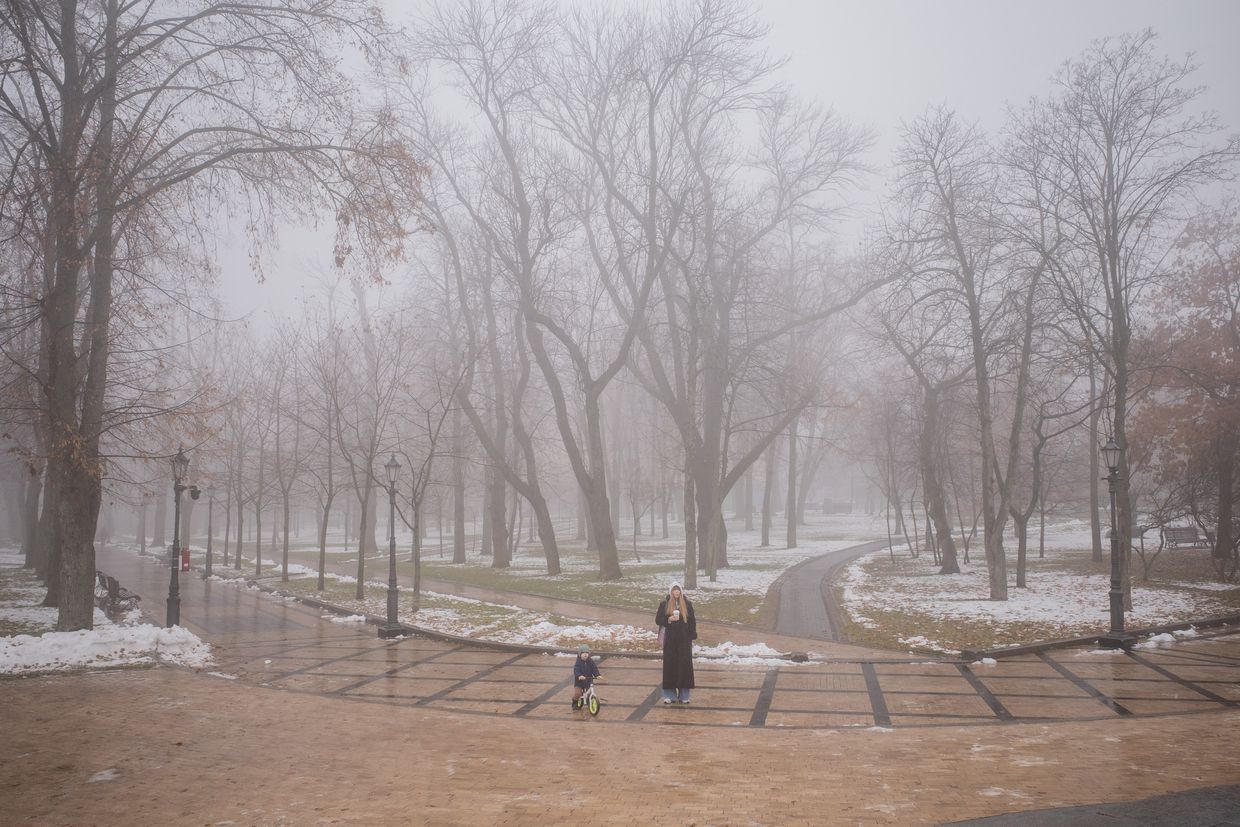 A woman with a child walks in a park on a foggy day in Kyiv, Ukraine, on Nov. 30, 2024, amid the Russian invasion. 