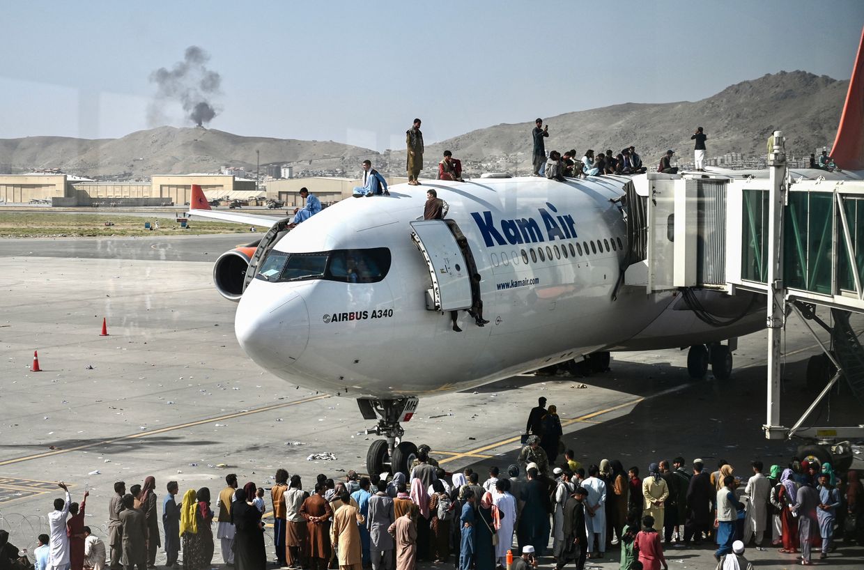 Afghans climb atop a plane as they wait at Kabul airport in Kabul, Afghanistan, on Aug. 16, 2021, amid the Taliban takeover. 