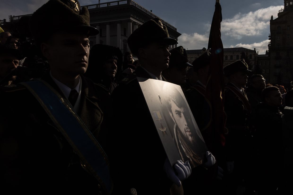 A Ukrainian service member holds a portrait of fallen soldier Dmytro Kotsiubailo during his funeral at Independence Square in Kyiv, Ukraine, on March 10, 2023. 