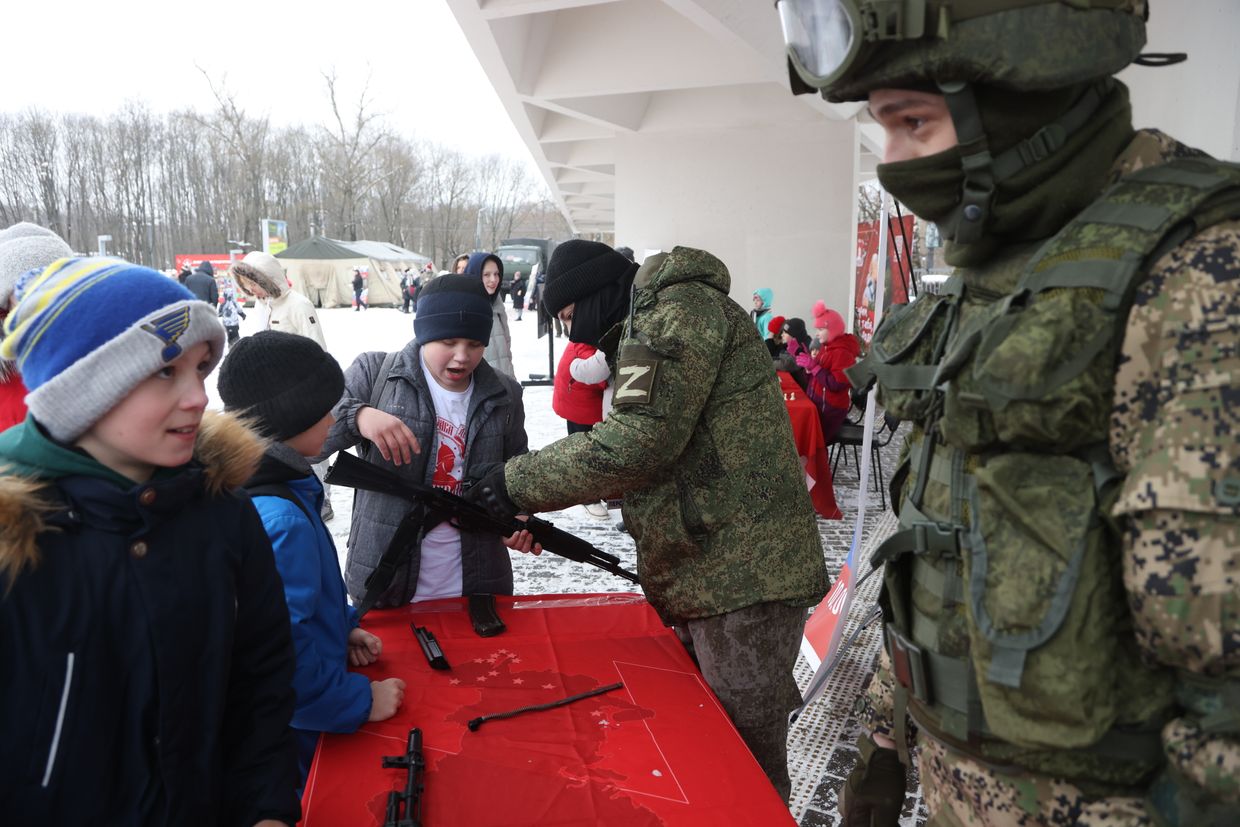 A Russian army officer wearing a “Z” symbol, associated with support of the Russian invasion of Ukraine, demonstrates a Kalashnikov assault rifle to a boy during a pro-military event in Krasnogorsk, Russia, on Feb. 24, 2024. 