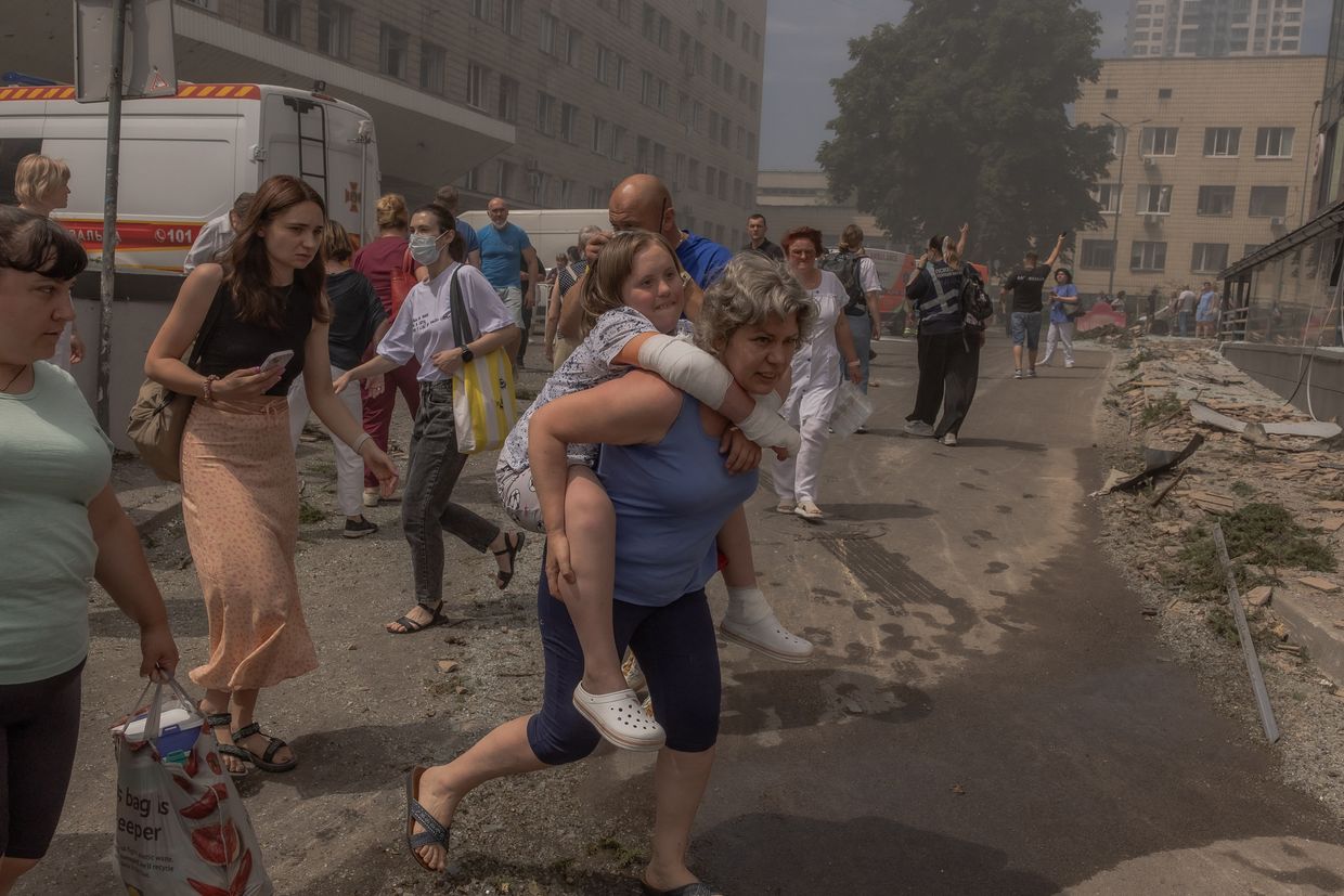 A woman carries a girl past the heavily damaged Ohmatdyt Children's Hospital after a Russian missile attack in Kyiv, Ukraine, on July 8, 2024.