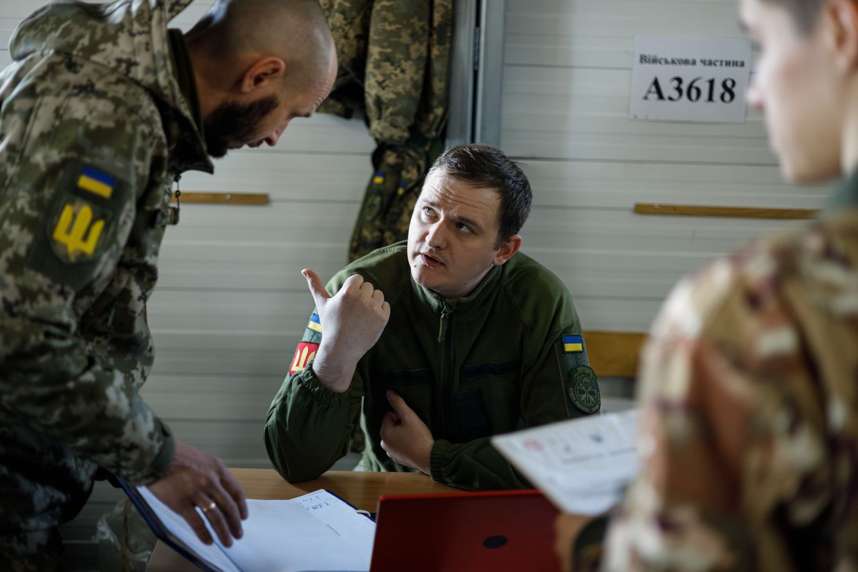 A serviceman speaks with a volunteer at a conscription point in Ukraine on March 26, 2024. 