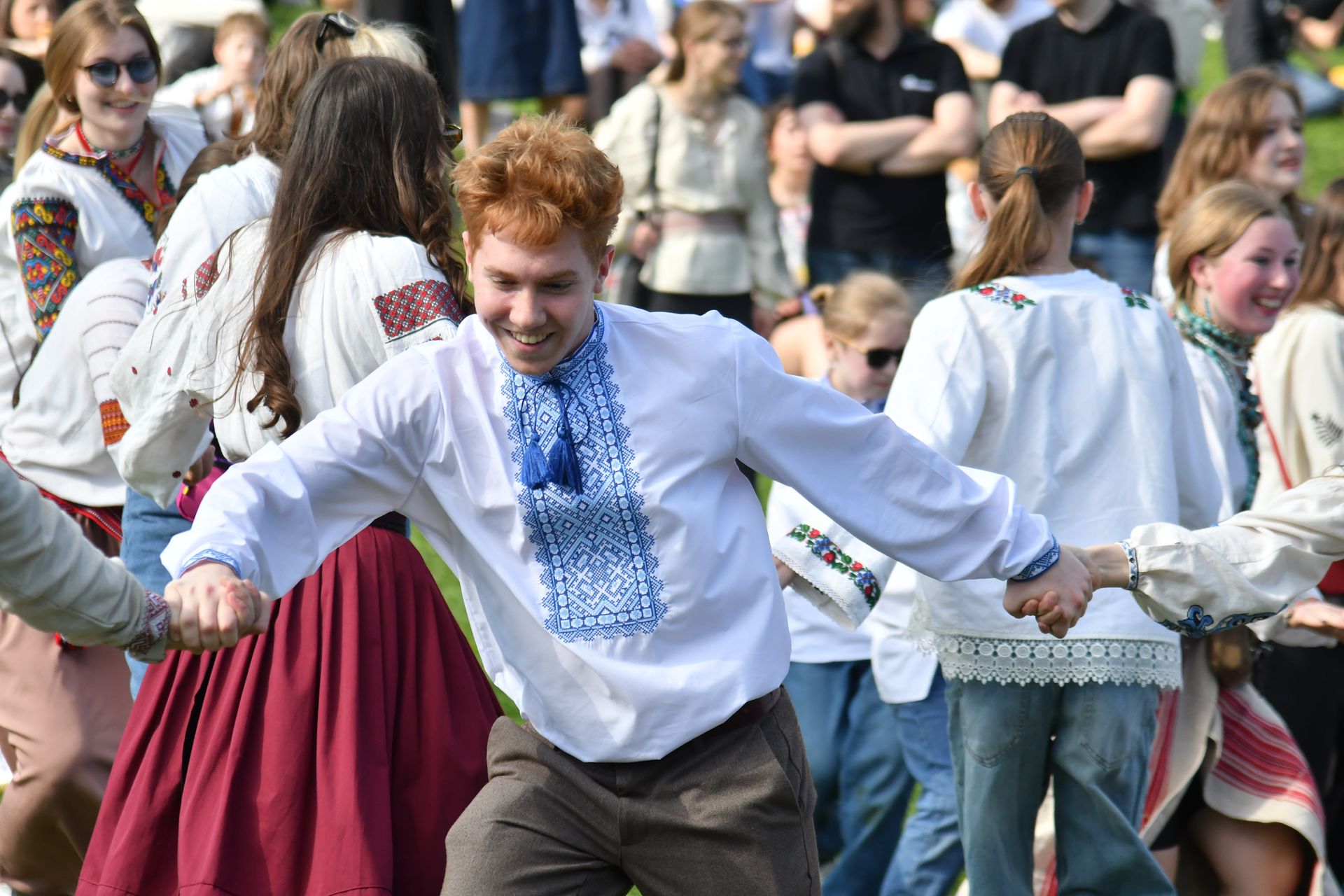 A man dances wearing a blue and white embroidered shirt
