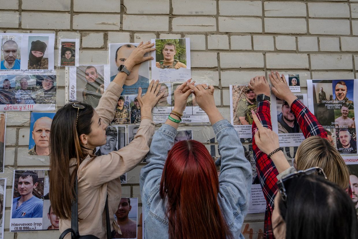 People post portraits of their missing or captured loved ones during the arrival of freed, injured, and severely wounded Ukrainian POWs in Chernihiv Oblast, Ukraine, on June 10, 2025