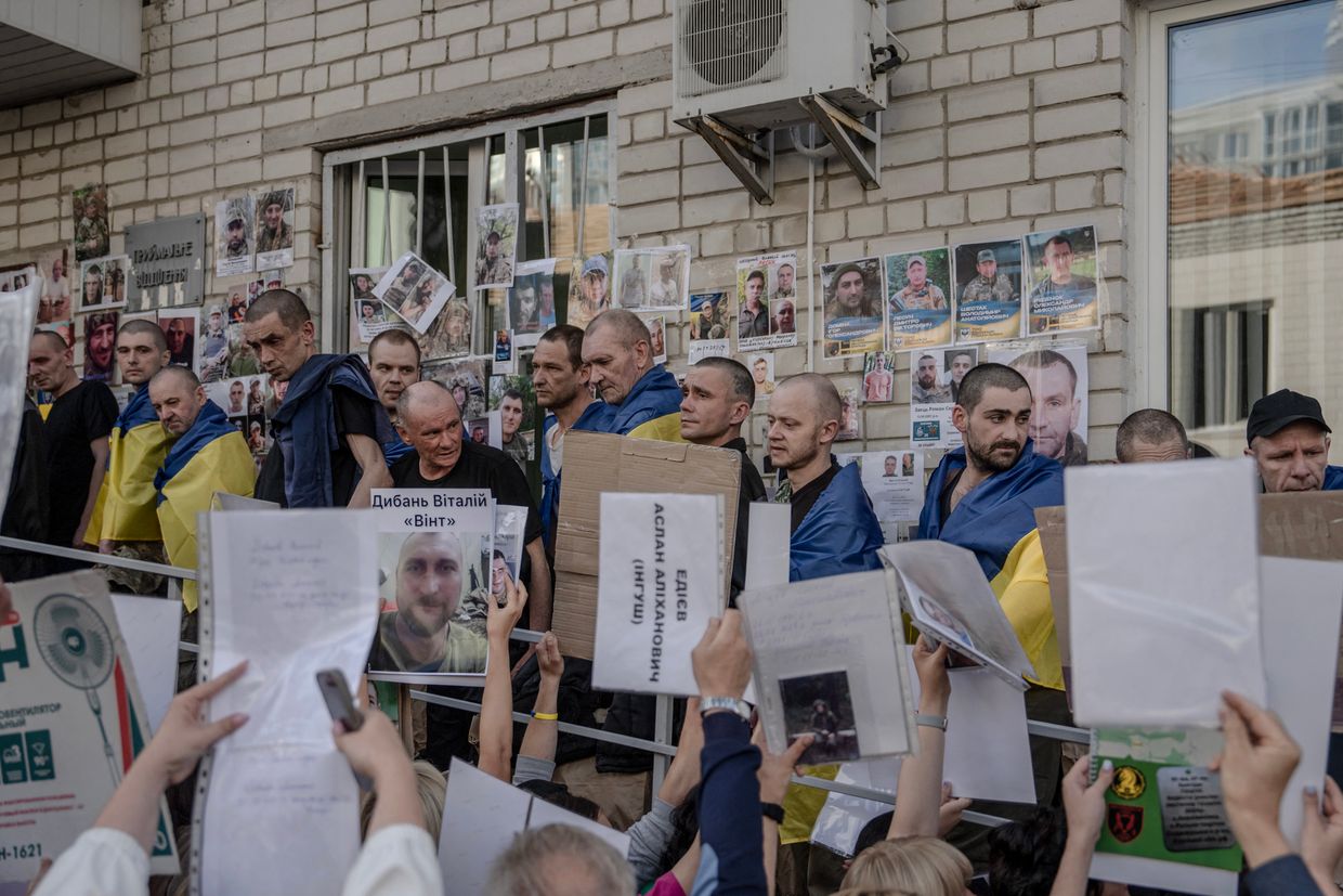Freed Ukrainian POWs look at portraits of missing or captured servicemen held by people during their arrival in Chernihiv Oblast, Ukraine, after a prisoner exchange on June 10, 2025.