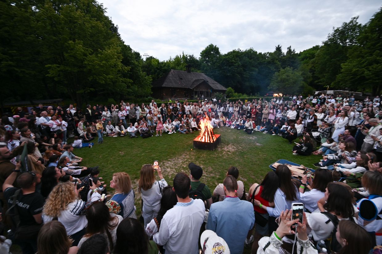 People sit by the bonfire during ChekaFest, a festival in memory of Iryna “Cheka” Tsybukh, in Lviv, Ukraine, on June 1, 2025.