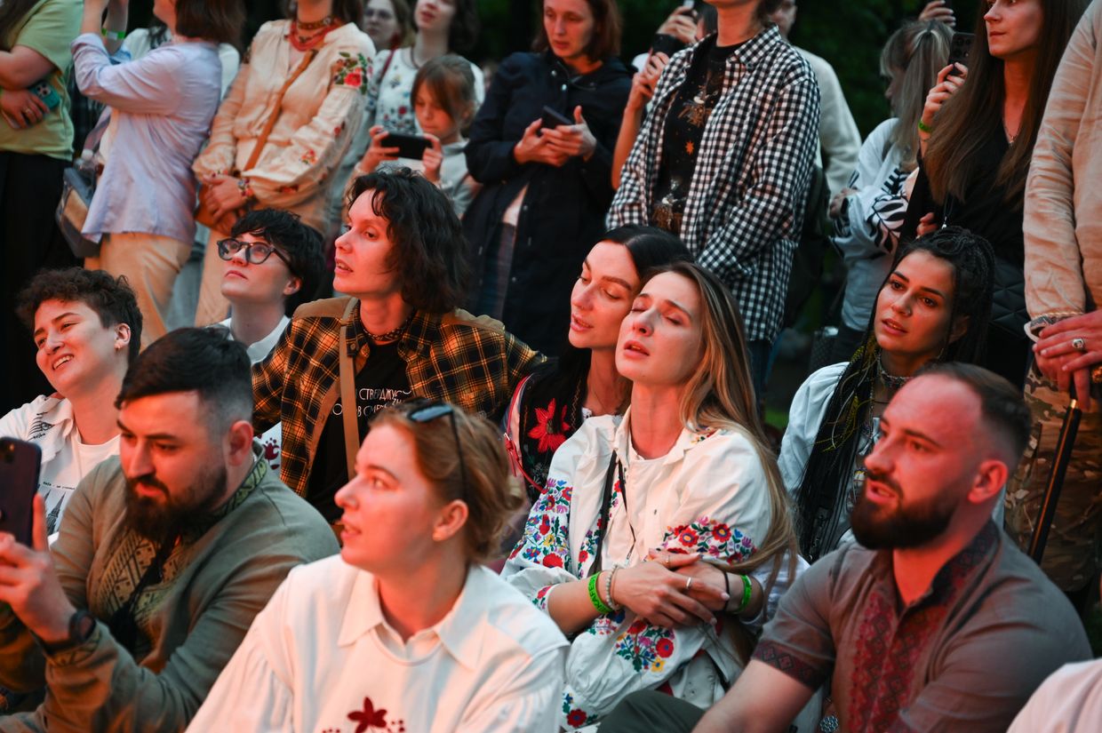 Iryna’s friends sit by the bonfire during ChekaFest, a festival in memory of Iryna “Cheka” Tsybukh, in Lviv, Ukraine, on June 1, 2025.