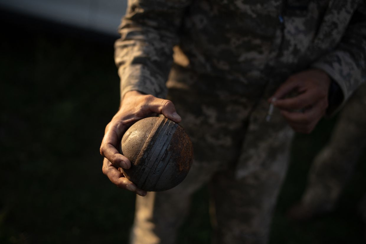 A soldier of a mobile anti-aircraft brigade holds an unexploded Russian cluster bomb in Starokostiantyniv, Khmelnytskyi Oblast, Ukraine, on July 8, 2024. 