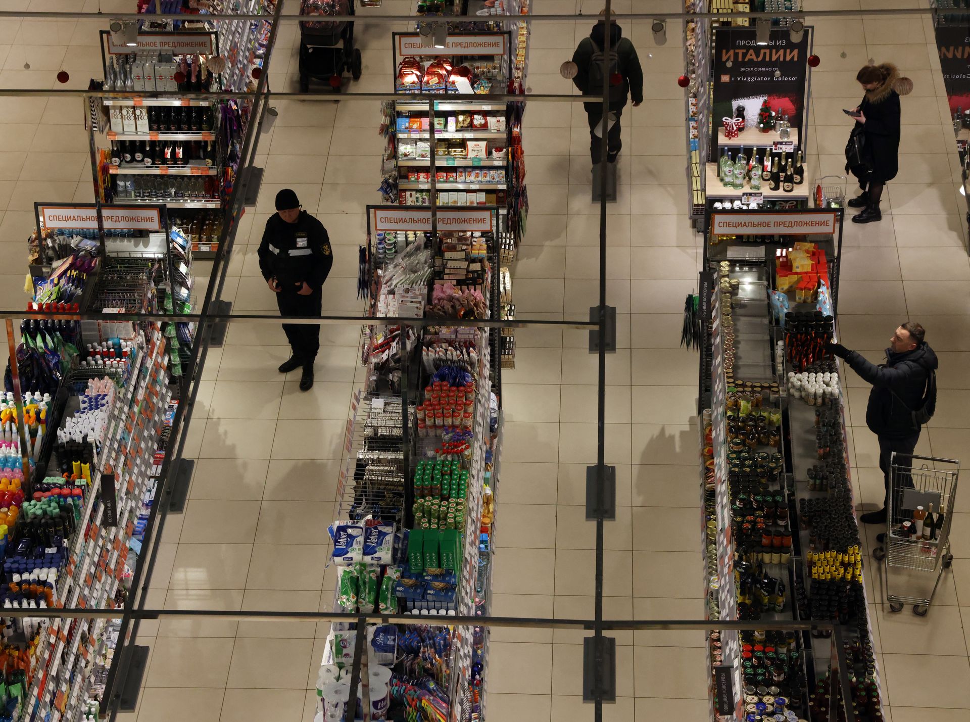Shoppers and a security guard look at grocery shelves inside a Miratorg supermarket in Moscow, Russia, on Dec. 23, 2022.