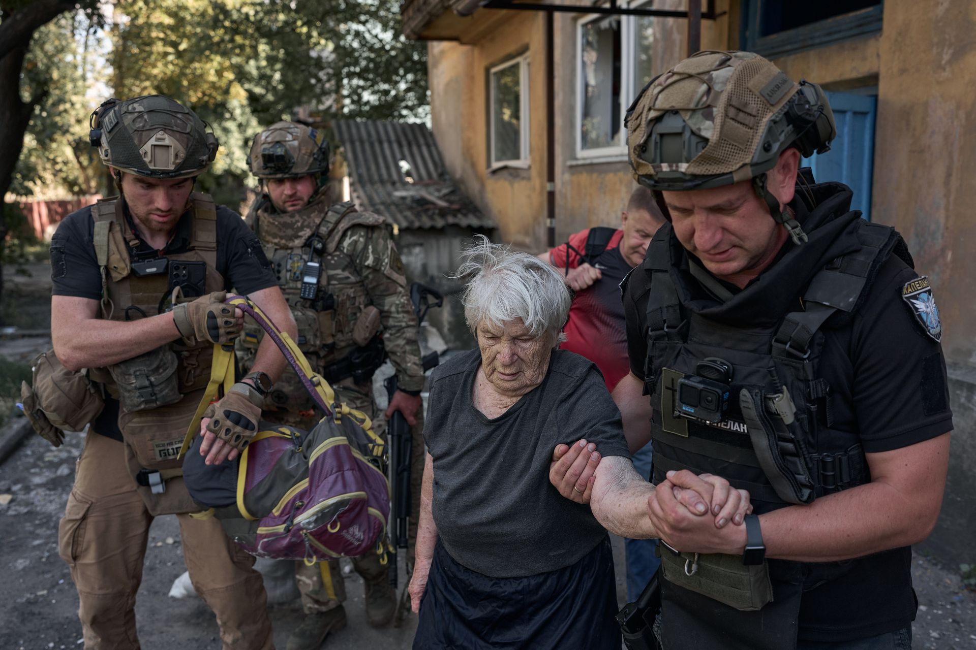 A woman is helped by volunteers as she is evacuated to a designated gathering point in Dobropillia, Donetsk Oblast, Ukraine, on Aug. 19, 2025.