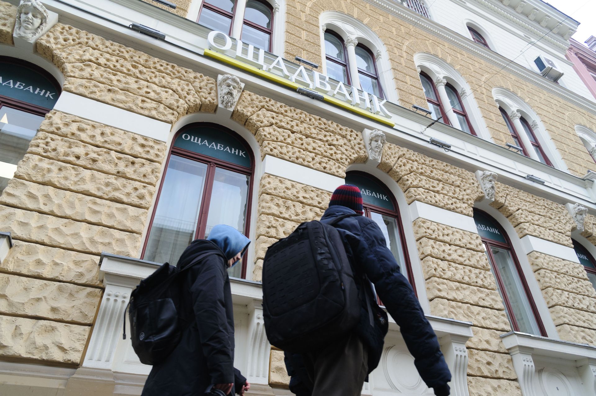 People walk past an Oschadbank branch, the state savings bank of Ukraine, in downtown Lviv, Ukraine, on Feb. 23, 2022.