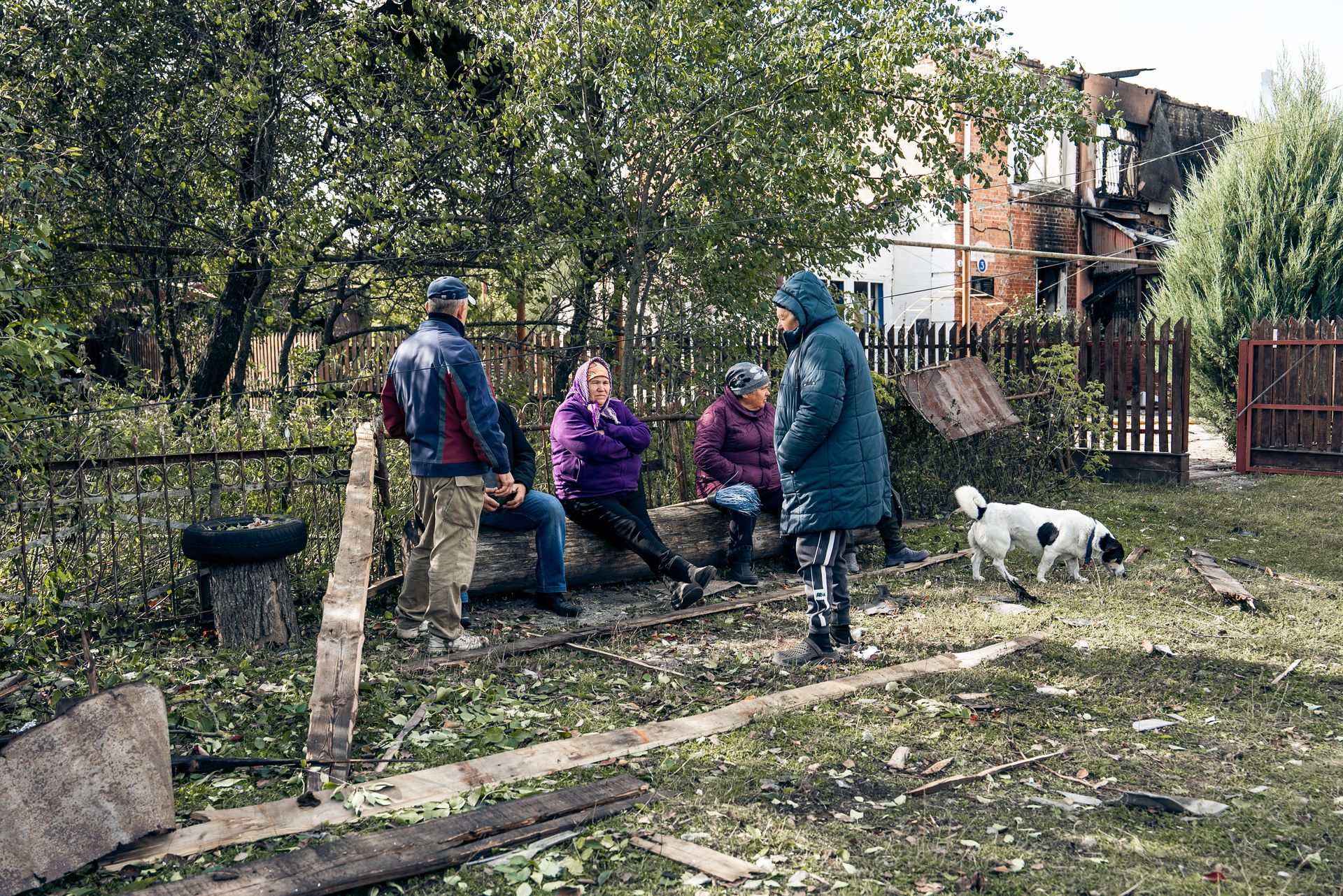 Local residents sit on a street near a destroyed building in Chernechchyna, Sumy Oblast, on Sept. 30, 2025.
