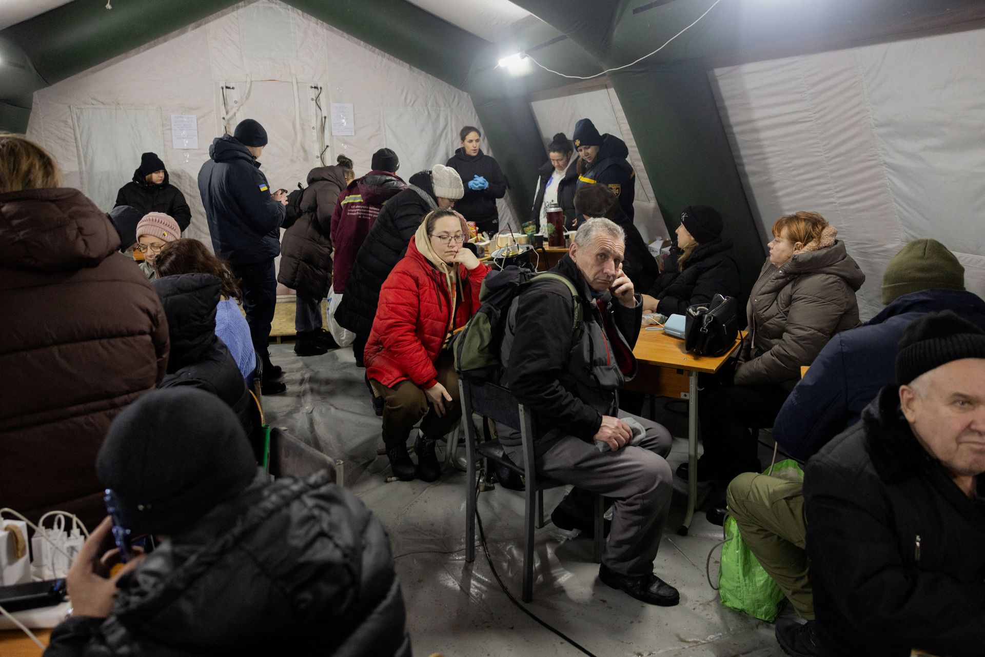 People charge their phones and warm themselves in heating tents set up by the State Emergency Service in Kyiv, Ukraine, on Jan. 11, 2026.