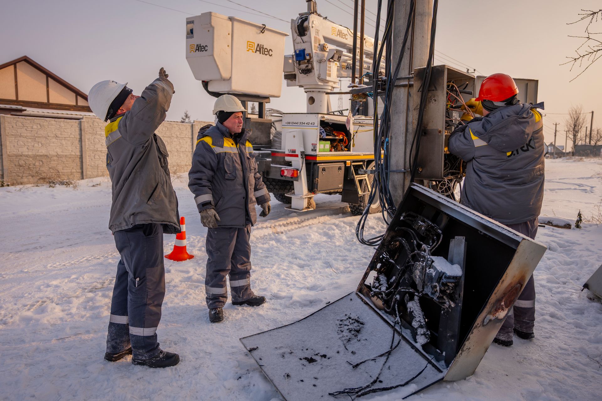 Electricians from DTEK, Ukraine’s energy company, inspect a damaged electrical box and related equipment on an electricity pylon in Kyiv Oblast, Ukraine, on Jan. 14, 2026