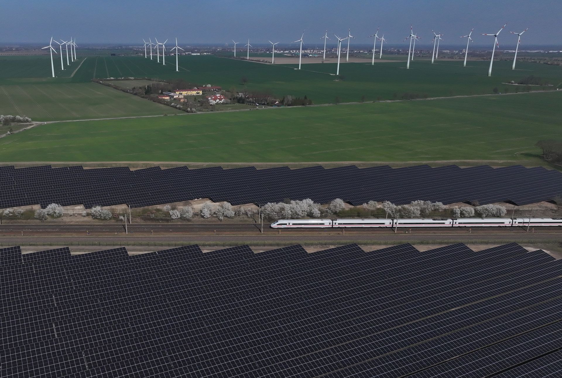 A high-speed Intercity Express train of German state railways Deutsche Bahn passes a solar energy park and wind turbines near Nauen, Germany, on April 2, 2025.