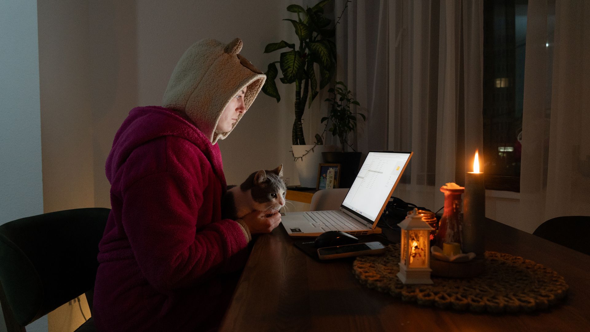 The Kyiv Independent videographer Olena Zashko works from home with her cat, Marseille, in her apartment in Kyiv, Ukraine, on Jan. 15, 2026.